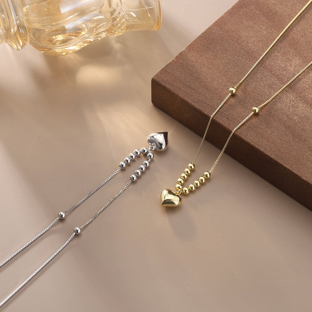 Zwei elegante Halsketten mit Herzanhängern, eine aus Silber und eine aus Gold, auf einem stilvollen Untergrund präsentiert.