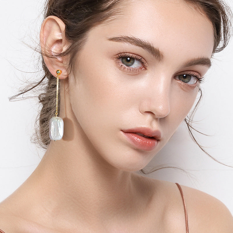 Model trägt Silber-Ohrringe mit hängender Barockperle