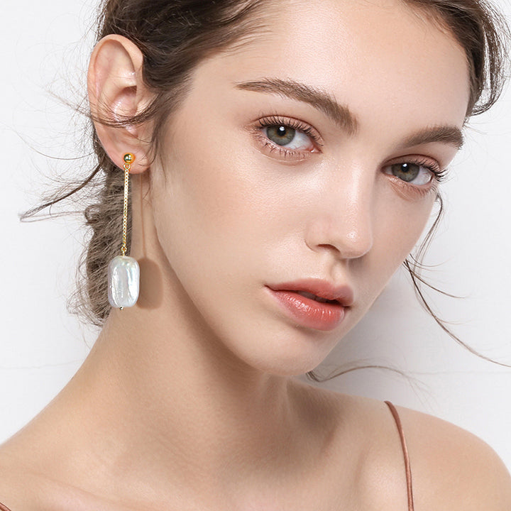 Model trägt Silber-Ohrringe mit hängender Barockperle