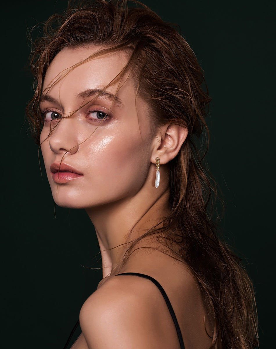 Model trägt vergoldete Ohrringe mit langer Barockperle