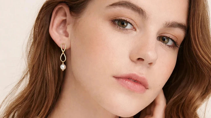 Model trägt vergoldete Infinity-Ohrringe mit Süßwasserperle